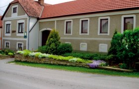 Weinbauernhof Eva Gruber, © Eva Gruber Traditionelles Bauernhaus mit gepflegtem Garten und roten Ziegeldächern.