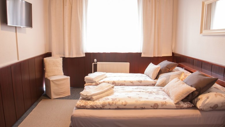 Pension Brandl, © Karin & Herbert Brandl Gemütliches Hotelzimmer mit zwei Einzelbetten, Fernseher, Stuhl und Fenster mit Vorhängen.