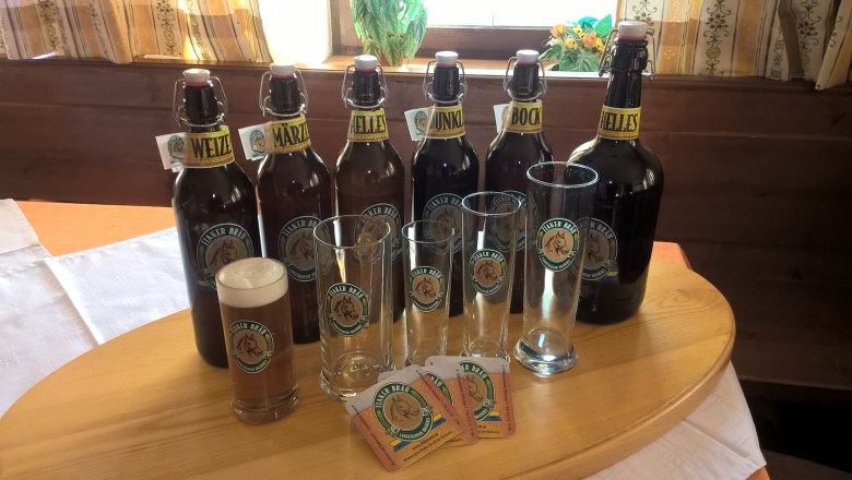 Fiakerbräu, © Braugasthaus zum Fiakerwirt Verschiedene Bierflaschen und Gläser der Marke Fiaker Bräu auf einem Tisch.