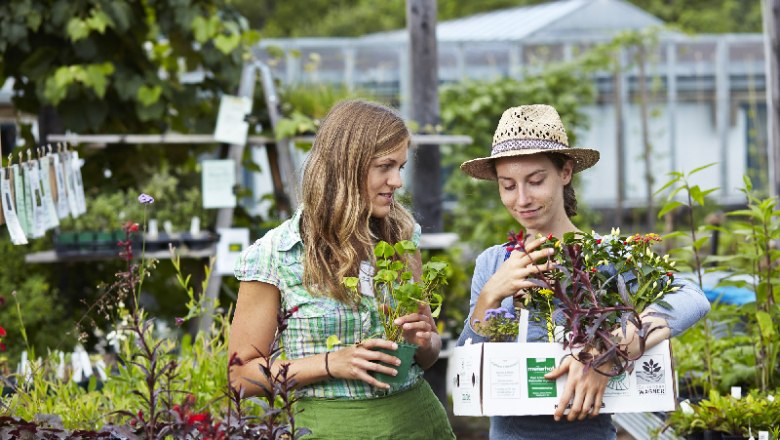 Arche Noah Shop, © Arche Noah Zwei Frauen in einem Gartenladen, eine mit Strohhut, halten Pflanzen in der Hand.