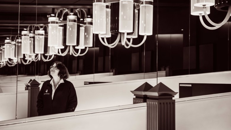 Steininger LOISIUM WeinWelt, © Pamela Schmatz Eine Frau steht in einem Raum mit großen, modernen Kronleuchtern und Spiegeln.