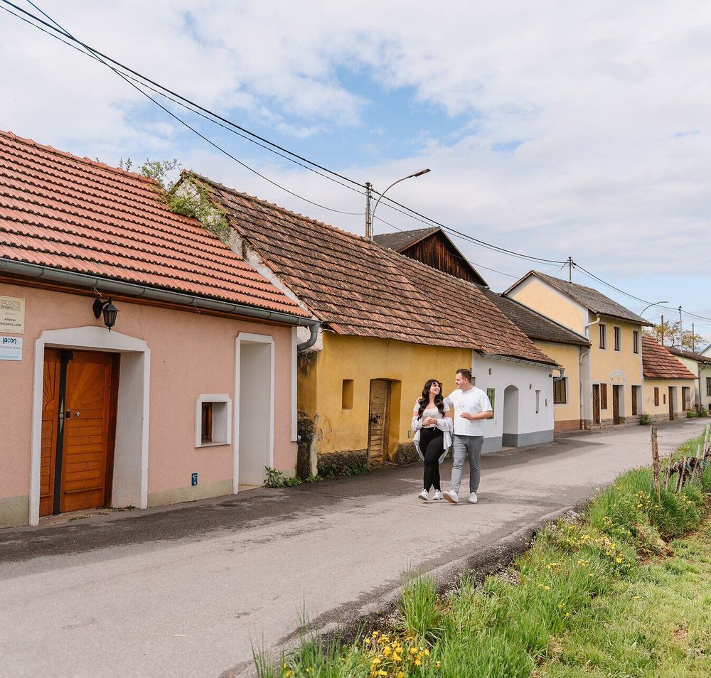 In der malerischen Kulisse des Kamptals schlendern Paare entspannt entlang der charmanten Häuserreihe. Die sanften Hügel und die blühenden Weinreben schaffen eine einladende Atmosphäre, die zum Verweilen und Genießen einlädt. Hier wird der Frühling mit all seinen Farben und Düften lebendig.