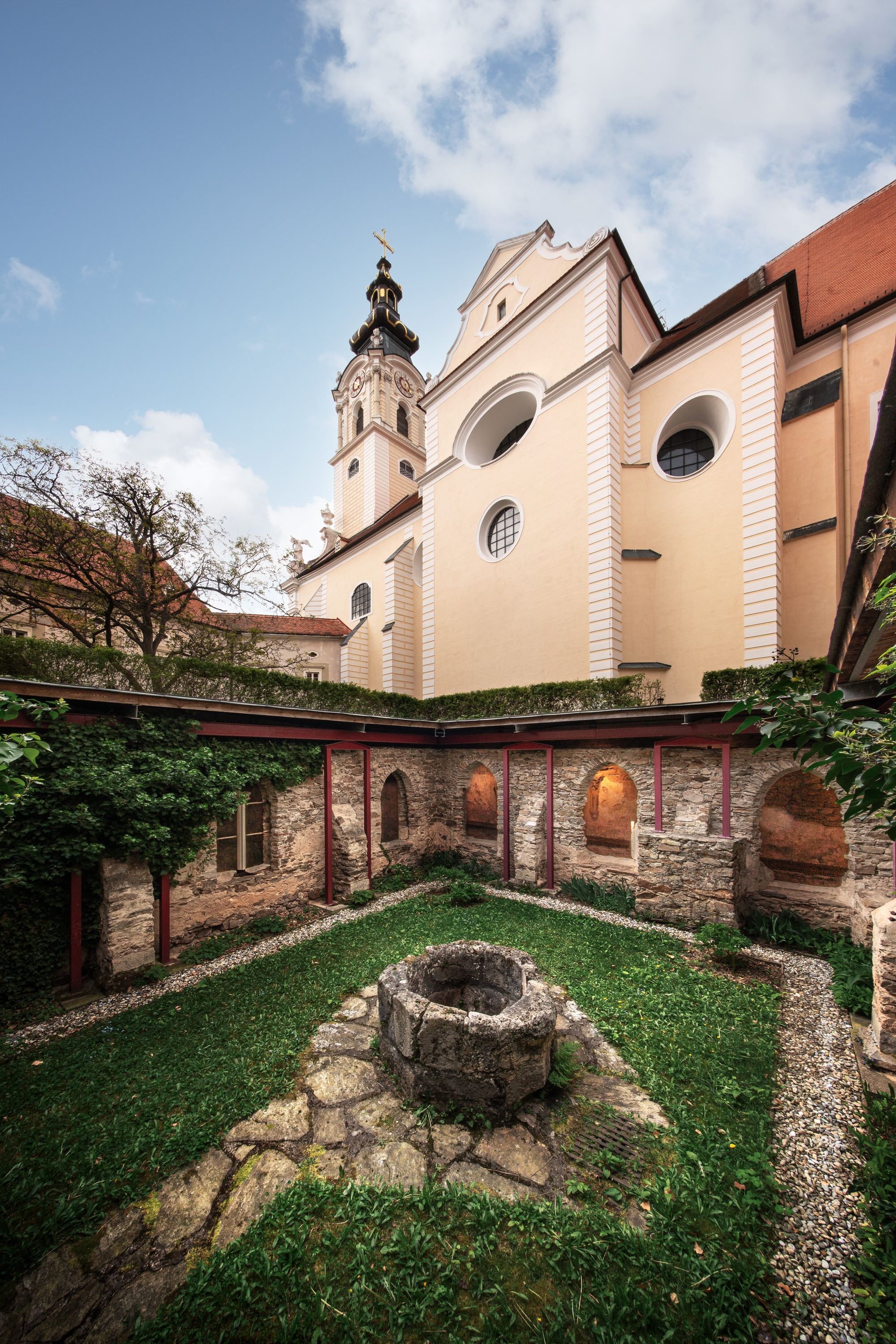 Innenhof des Stifts Altenburg mit Brunnen und Kirchturm im Hintergrund.