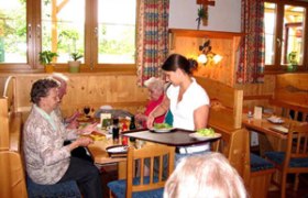 Innenansicht eines traditionellen österreichischen Heurigen mit Gästen und Bedienung.