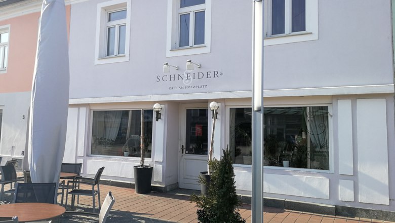 Außenansicht eines Cafés mit Terrasse und Sonnenschirm.