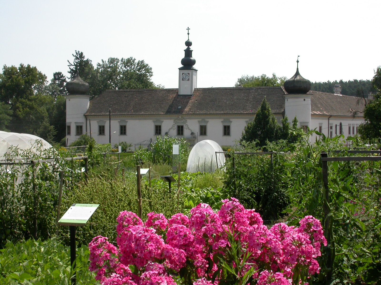 Barockes Gebäude mit Zwiebeltürmen hinter einem blühenden Garten.