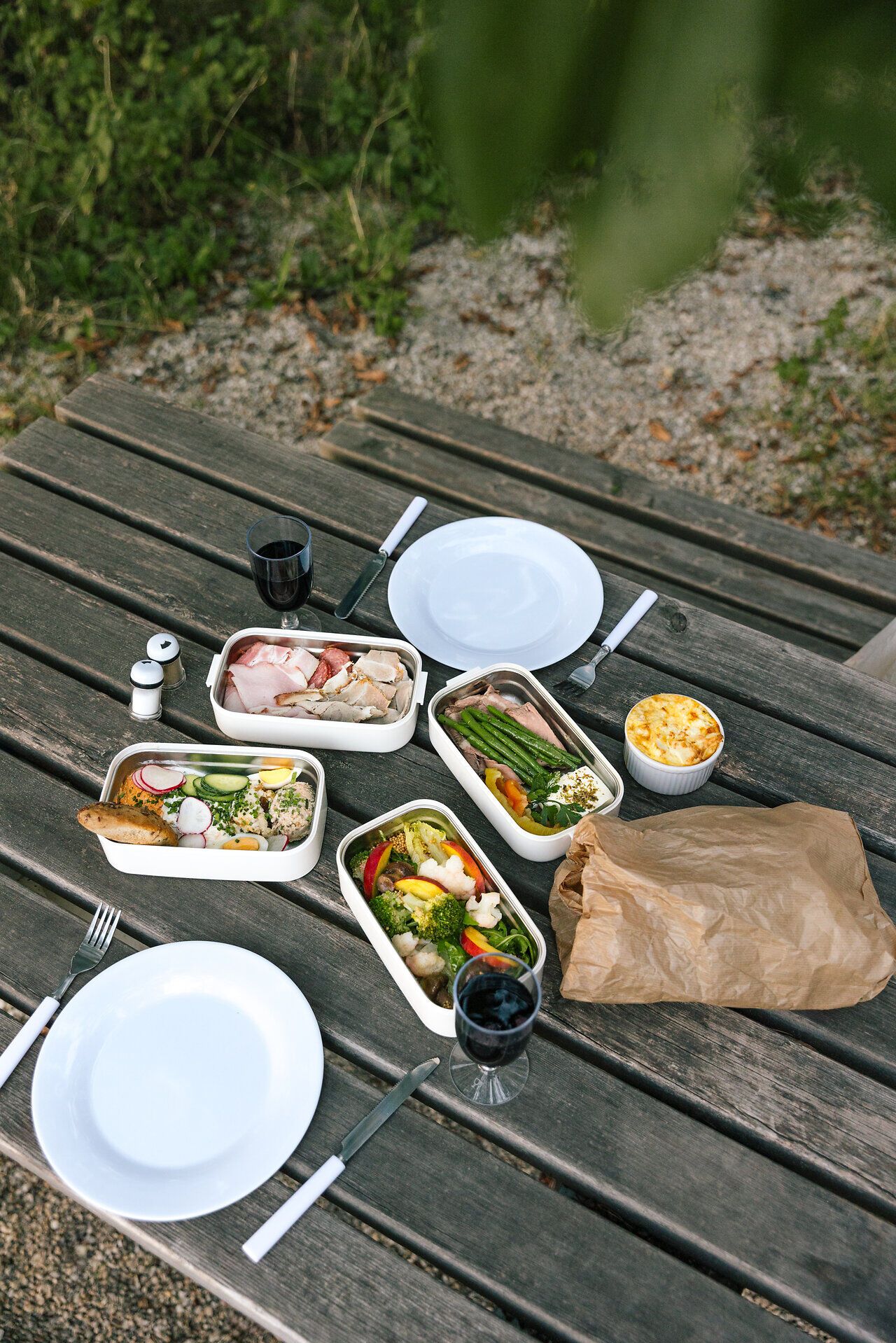 Ein einladendes Picknick auf einem rustikalen Holztisch, umgeben von der üppigen Natur des Kamptals. Frische, bunte Speisen und erfrischende Getränke laden dazu ein, die warmen Sommertage in vollen Zügen zu genießen. Die Atmosphäre ist entspannt und harmonisch, perfekt für eine Auszeit im Freien.
