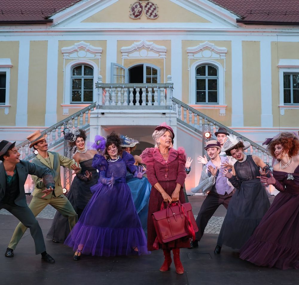 Künstler und Künstlerinnen in bunten Kostümen vor dem Schloss Haindorf.