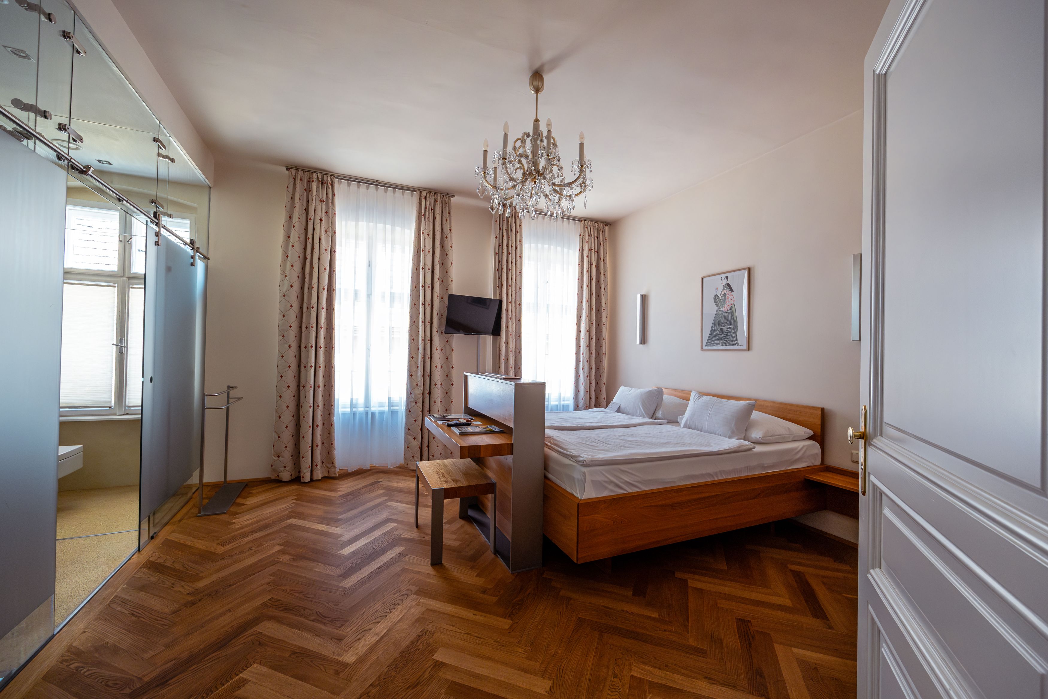 Elegantes Hotelzimmer mit Doppelbett, Parkettboden und Kronleuchter.