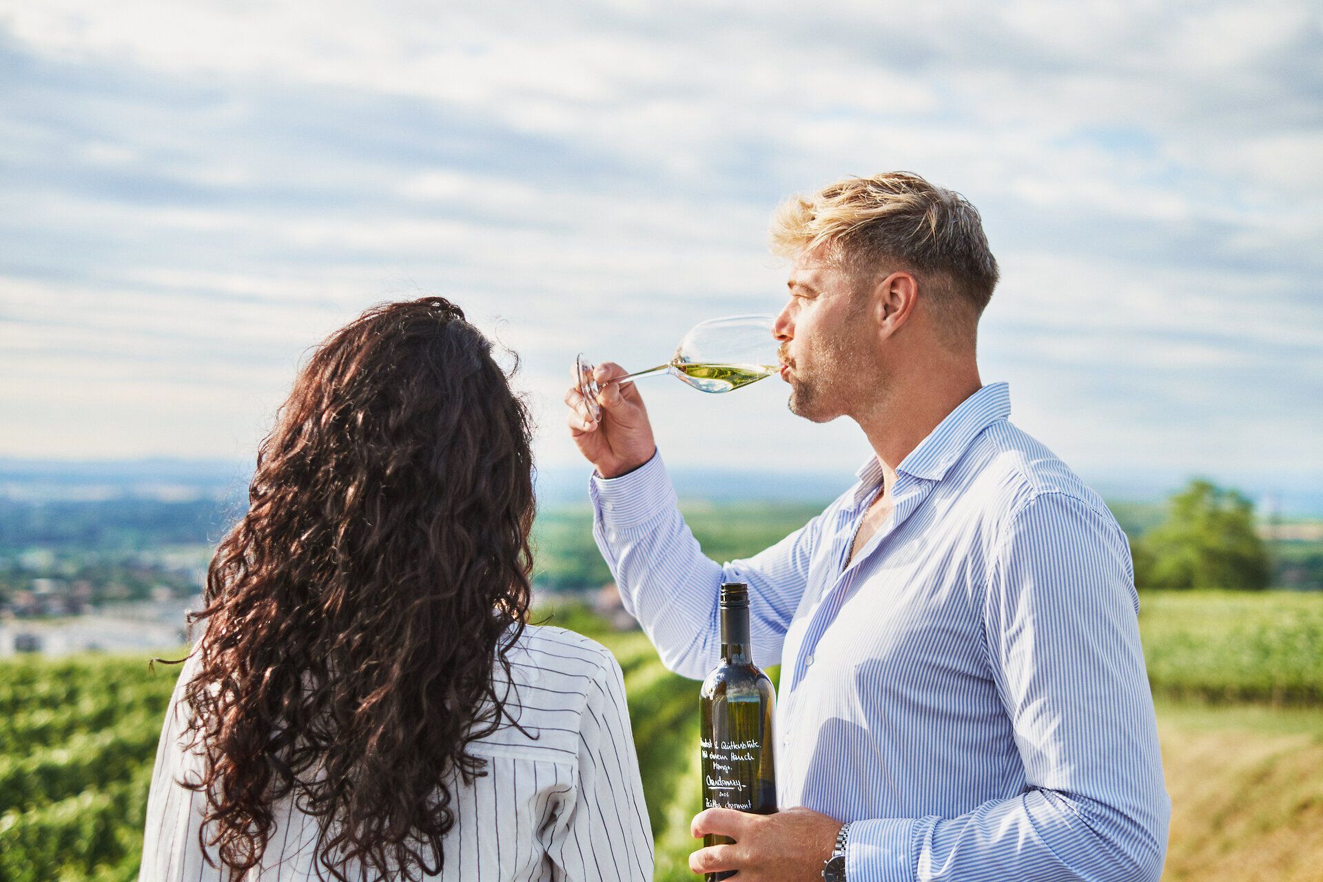 Inmitten der sanften Hügel des Kamptals genießen zwei Menschen den feinen Wein, umgeben von üppigen Weinreben. Die malerische Landschaft strahlt eine einladende Atmosphäre aus, die zum Verweilen und Entspannen einlädt.
