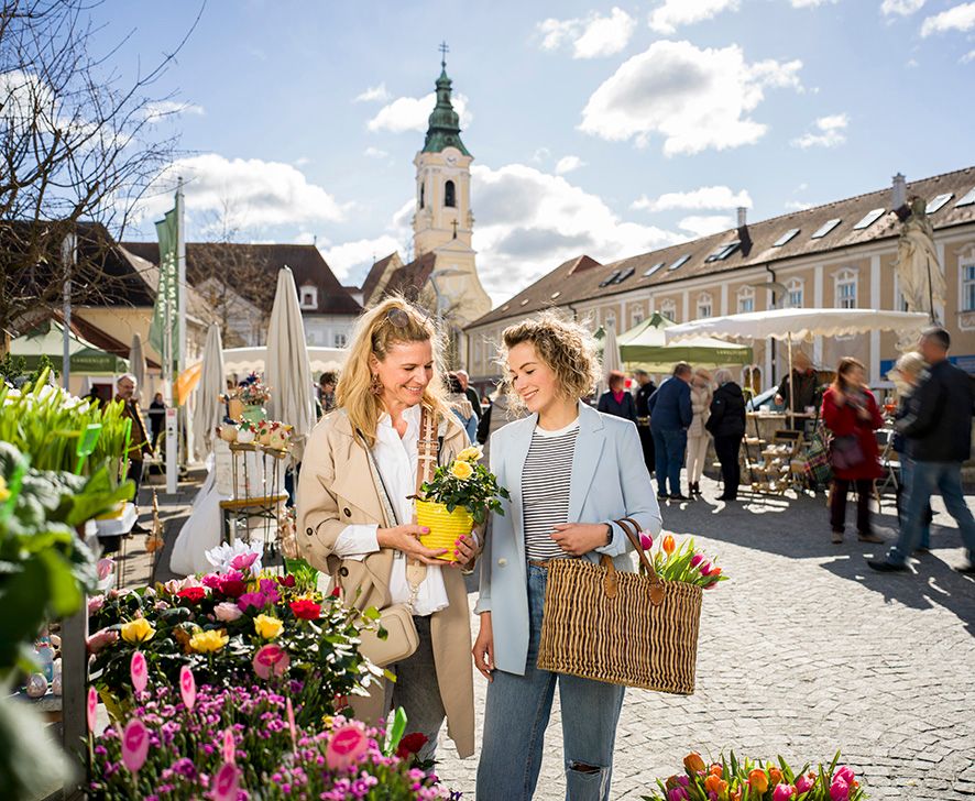 2 Frauen auf einem Markt mit Blumen in der Hand. 