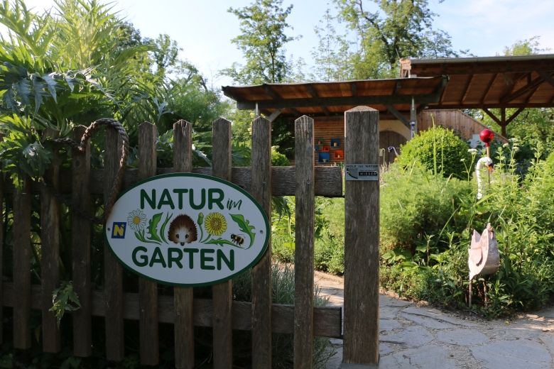 Eingang zu einem Garten mit einem Schild 'Natur im Garten'.