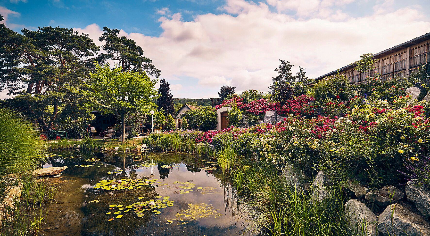 Ein malerischer Garten lädt zum Verweilen ein, umgeben von üppigen Blumen und sanften Wasserflächen. Die harmonische Verbindung von Natur und Ruhe schafft eine Oase der Entspannung, ideal für einen erholsamen Tag im Freien.