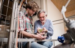 Zwei Männer die Hopfen in eine Schüssel füllen. 