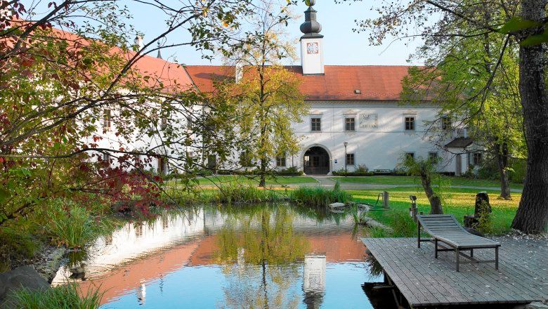 Innenhof von Schloss Schiltern mit Teich und Liegestuhl.
