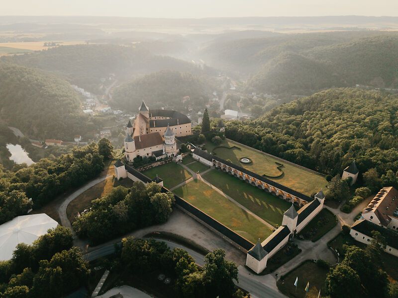 Luftaufnahme der Rosenburg inmitten grüner Wälder und Hügel.