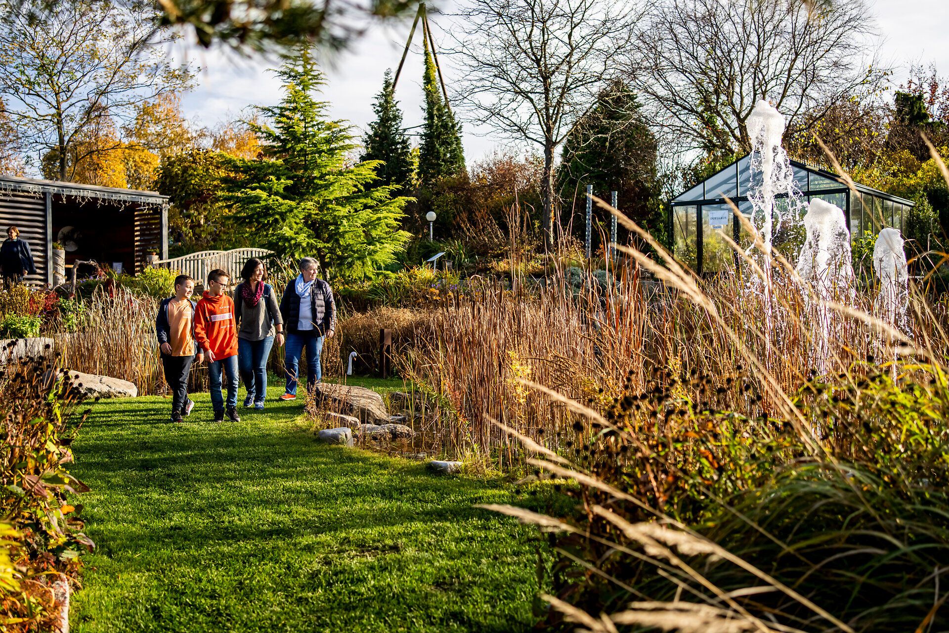 In den Kittenberger Erlebnisgärten entfaltet sich der Herbst in voller Pracht. Die bunten Blätter der Bäume und die sanften Wellen des Grases laden zu einem entspannten Spaziergang ein. Familien genießen die harmonische Atmosphäre und die Schönheit der Natur.
