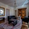 Elegantes Wohnzimmer mit antikem Schrank, großem Spiegel, schwarzen Ledermöbeln und einem Kronleuchter.