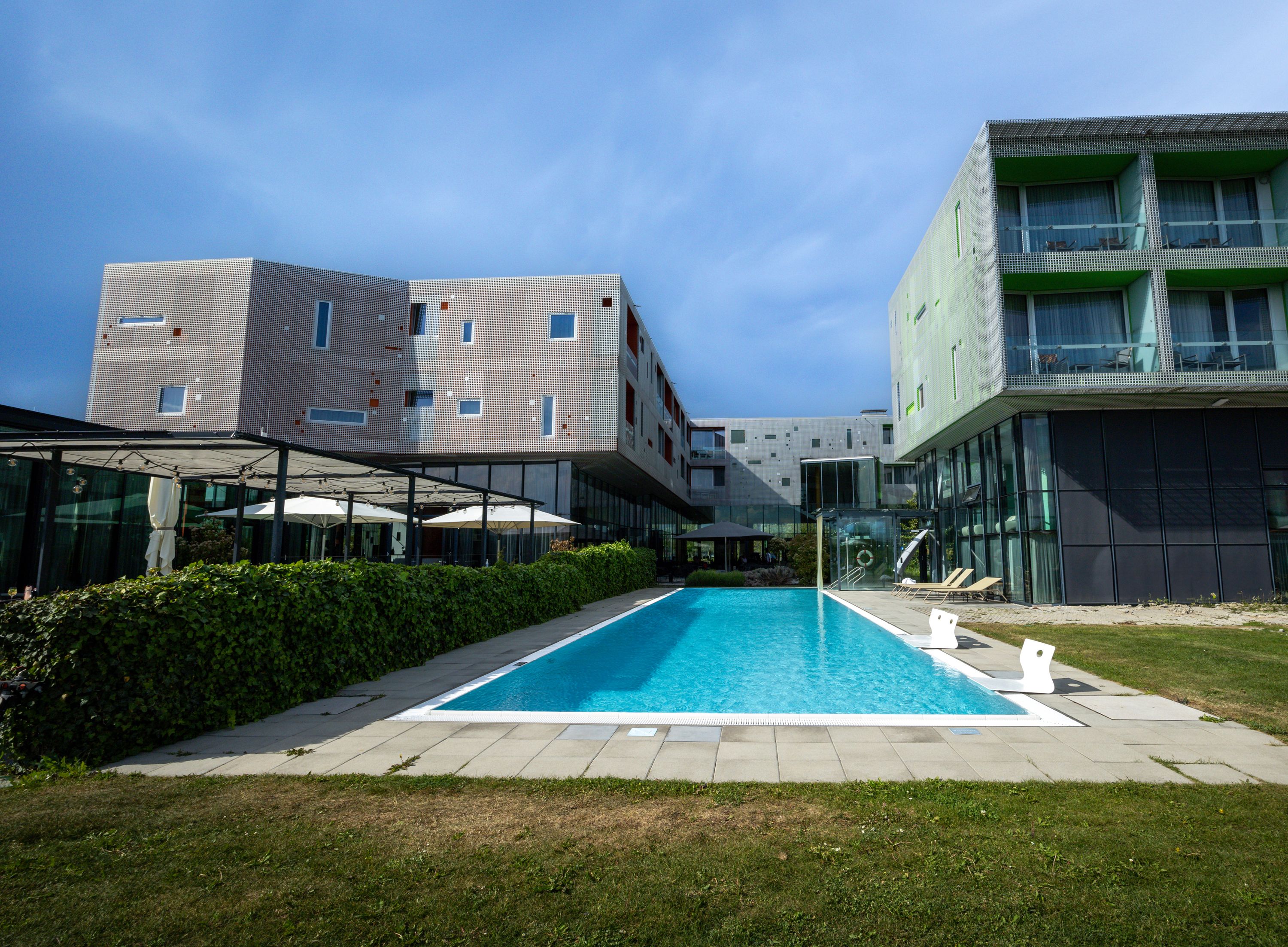 Modernes Gebäude mit Pool und Terrasse im Vordergrund.