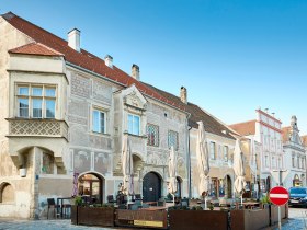 Die charmanten, historisch verzierten Fassaden der Stadtmauerstadt laden zum Verweilen ein. Unter den schattigen Sonnenschirmen der gem&uuml;tlichen Caf&eacute;s genie&szlig;en Besucher die entspannte Atmosph&auml;re und die malerische Umgebung. Hier verschmelzen Geschichte und Lebensfreude zu einem unvergesslichen Erlebnis.