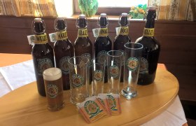 Verschiedene Bierflaschen und Gläser der Marke Fiaker Bräu auf einem Tisch.