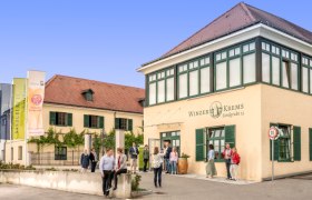 Geb&auml;ude von Winzer Krems mit Menschen davor.