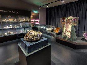 In einem faszinierenden Raum voller glitzernder Amethysten entfaltet sich die Sch&ouml;nheit der Natur in ihrer reinsten Form. Die funkelnden Kristalle strahlen in verschiedenen Violettt&ouml;nen und laden Besucher ein, die Wunder der Mineralienwelt zu entdecken. Ein Ort der Ruhe und Inspiration, der die Sinne verzaubert.