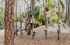 Kinder spielen auf einem Kletterparcours im Freien.