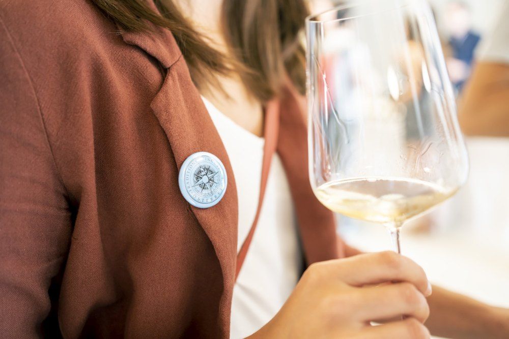 Eine Frau hält ein Weinglas mit Weißwein in der Hand. 