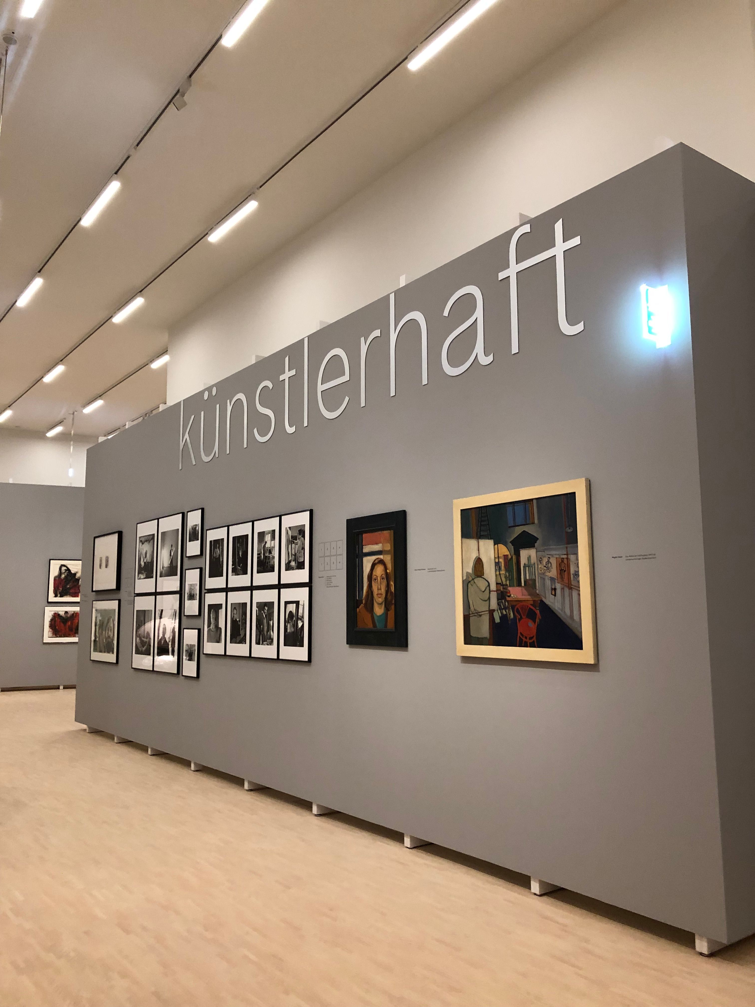 Ausstellungswand mit Kunstwerken und dem Schriftzug 'künstlerhaft'.