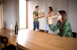 Frau verkostet Wein im Weinglas. Im Hintergrund Frau und Mann.