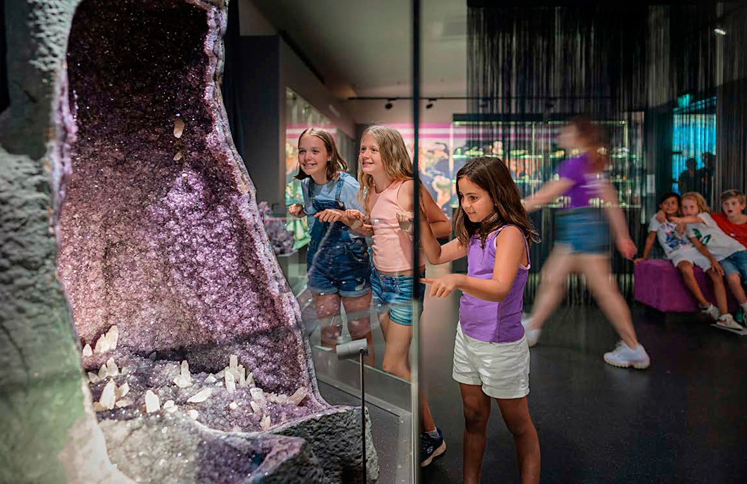 Kinder betrachten eine große Amethystgeode in einem Museum.