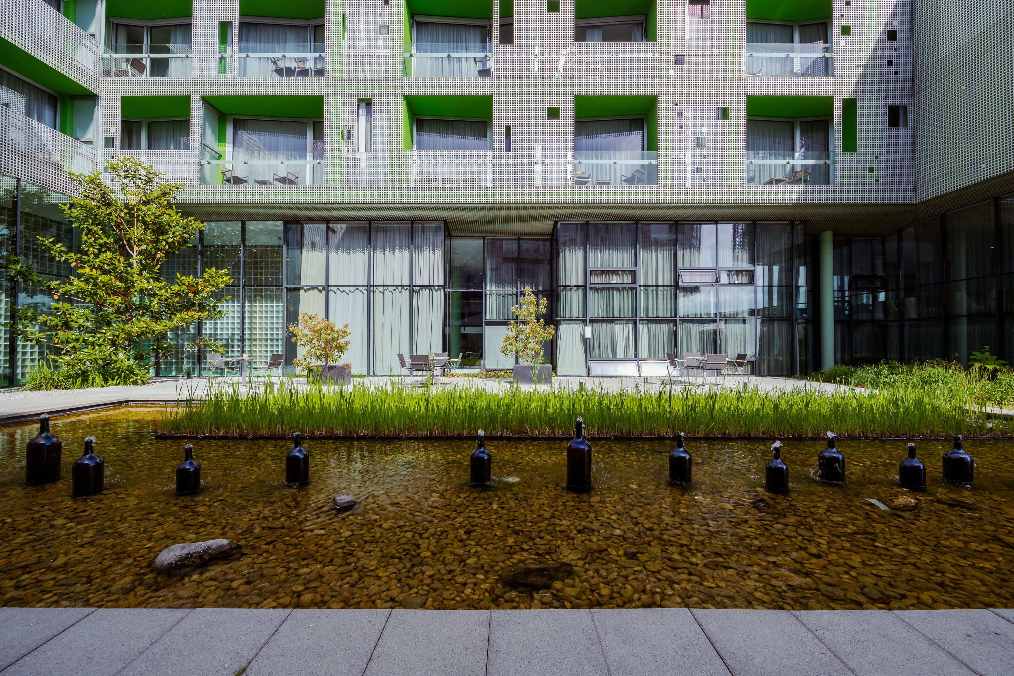 Moderner Gebäudekomplex mit grünem Innenhof und Wasserbecken.