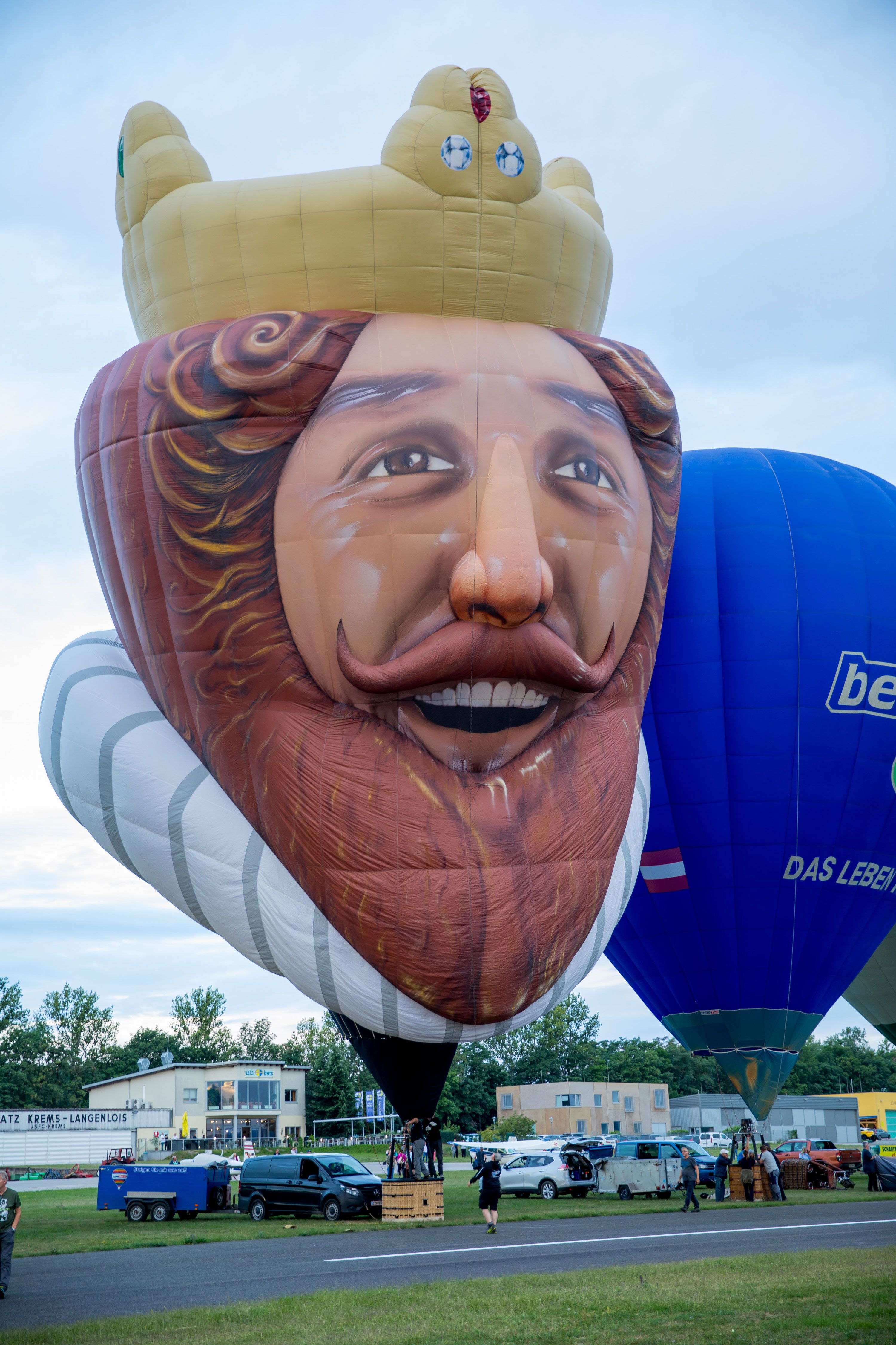 Heißluftballon in Form eines lächelnden Königs bei einem Ballonfestival.